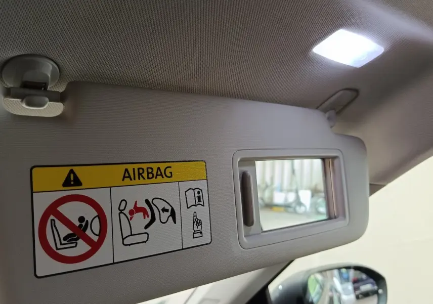 Détail du pare-soleil côté conducteur avec miroir et étiquette d'avertissement airbag dans un Volkswagen Taigo gris foncé.