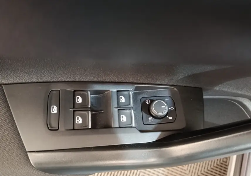Gros plan sur les commandes de lève-vitres et réglage des rétroviseurs côté conducteur du Volkswagen Taigo gris foncé 2023.
