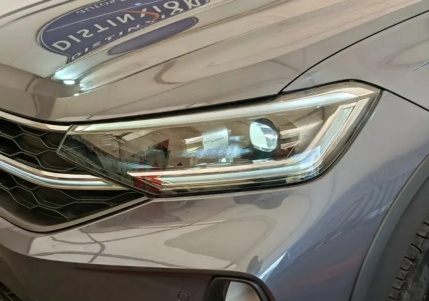 Gros plan sur le phare avant droit gris foncé du Volkswagen Taigo 1.5 TSI 150 DSG Style 2023 avec calandre noire.
