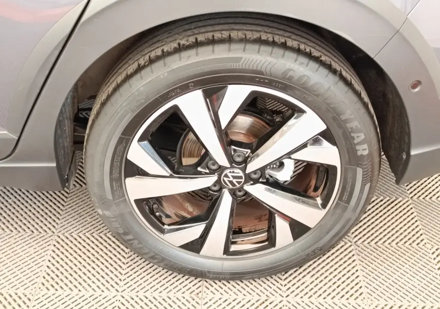 Gros plan sur la roue avant droite gris foncé du Volkswagen Taigo 2023 avec jante alliage bicolore et logo VW central.