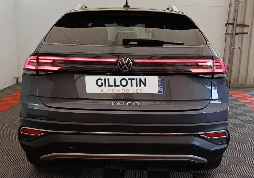 Vue arrière d’un Volkswagen Taigo gris foncé 2023 avec feux arrière LED allumés dans un garage.