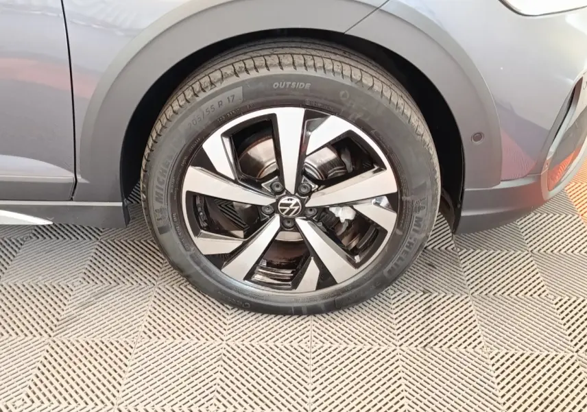 Gros plan sur la roue avant gauche et la jante en alliage du Volkswagen Taigo gris foncé 2023.