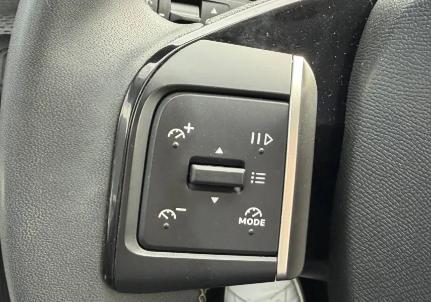 Gros plan sur les commandes de régulateur de vitesse à gauche du volant d’une Citroën C3 noire 2025.