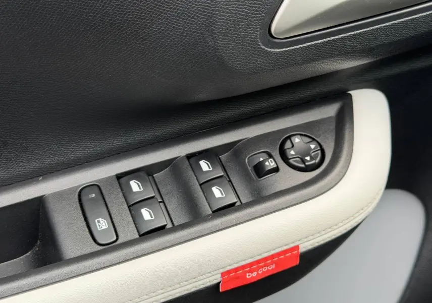 Détail des commandes de lève-vitres et réglage des rétroviseurs sur la portière intérieure noire et blanche du Citroën C3 2025.
