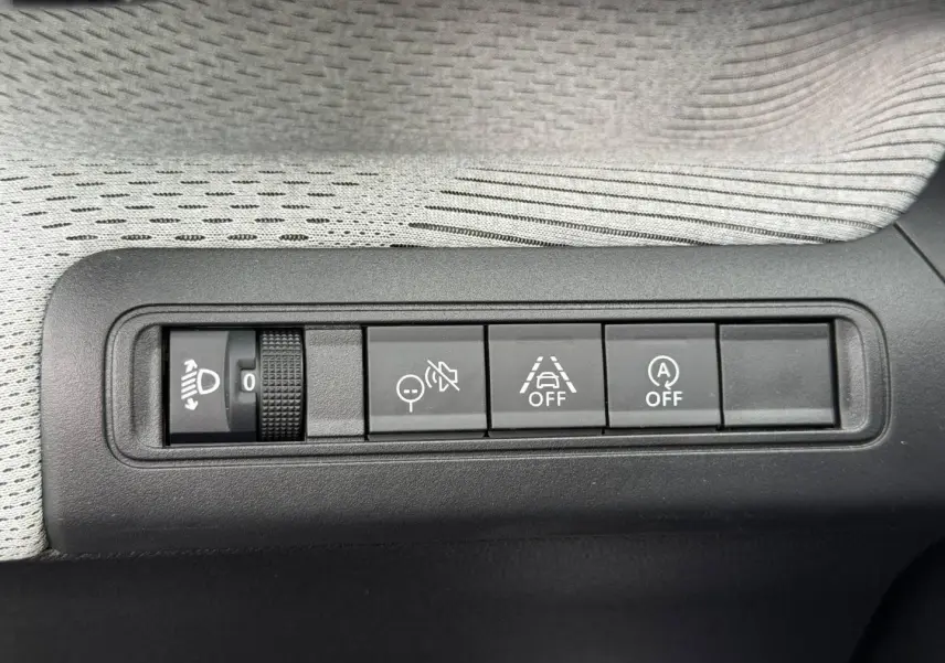Gros plan sur les commandes de réglage des phares et d'assistance à la conduite dans une Citroën C3 noire, version 2025.