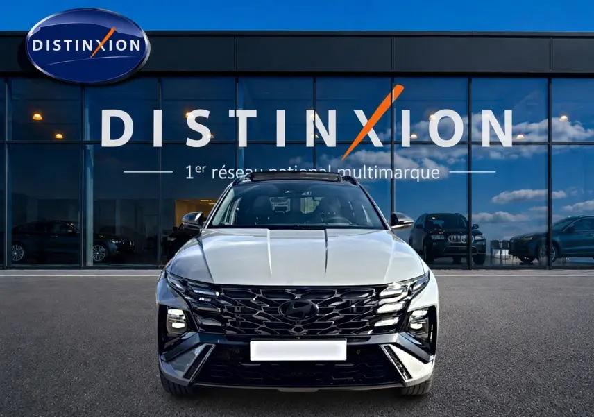 Vue avant du Hyundai Tucson gris shadow avec calandre noire et phares LED, devant une vitrine Distinxion.