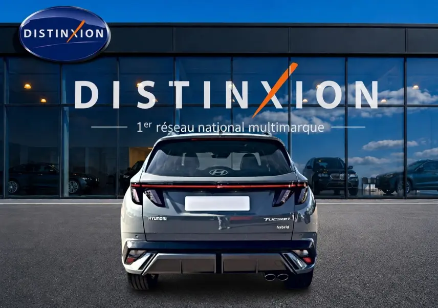 Vue arrière du Hyundai Tucson gris shadow hybride, avec feux LED et double sortie d'échappement visible devant une vitrine Distinxion.