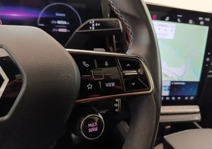 Gros plan sur le volant cuir et suede avec commandes multifonctions, écran tactile et tableau de bord numérique du Renault Austral gris clair.