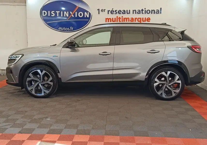 Profil droit du Renault Austral gris clair 2024 avec jantes alliage et toit noir contrasté en intérieur showroom.