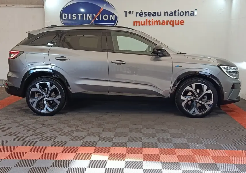 Profil droit d’un Renault Austral gris clair 2024 avec jantes alliage distinctives et toit noir en showroom.