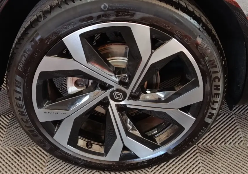 Gros plan sur la roue avant droite du Renault Austral gris clair avec jante Alpine et pneu Michelin.