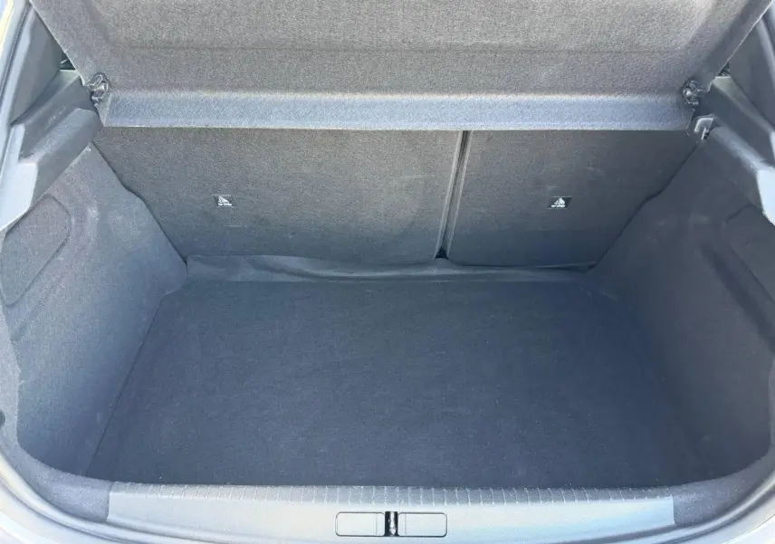 Coffre ouvert de la Peugeot 208 1.2 100ch Allure gris Artense, montrant l'espace de chargement vide et la banquette arrière rabattable.
