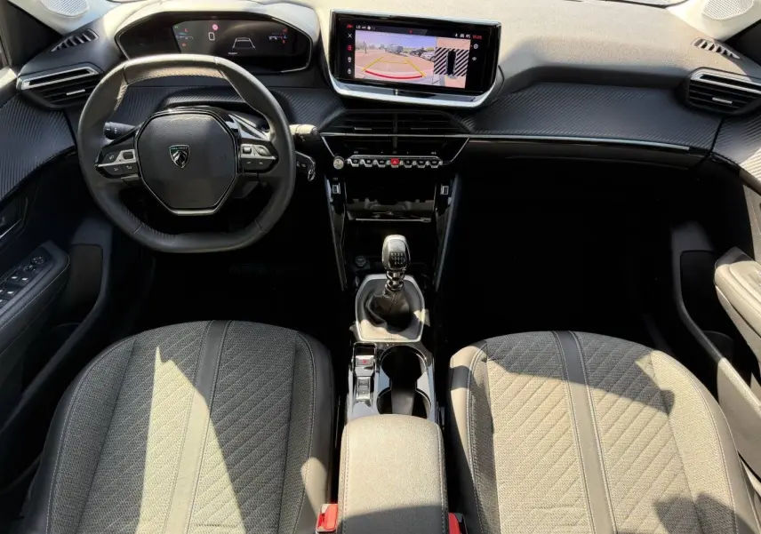 Vue intérieure de face du poste de conduite de la Peugeot 208 gris Artense, volant compact et écran tactile avec caméra de recul.