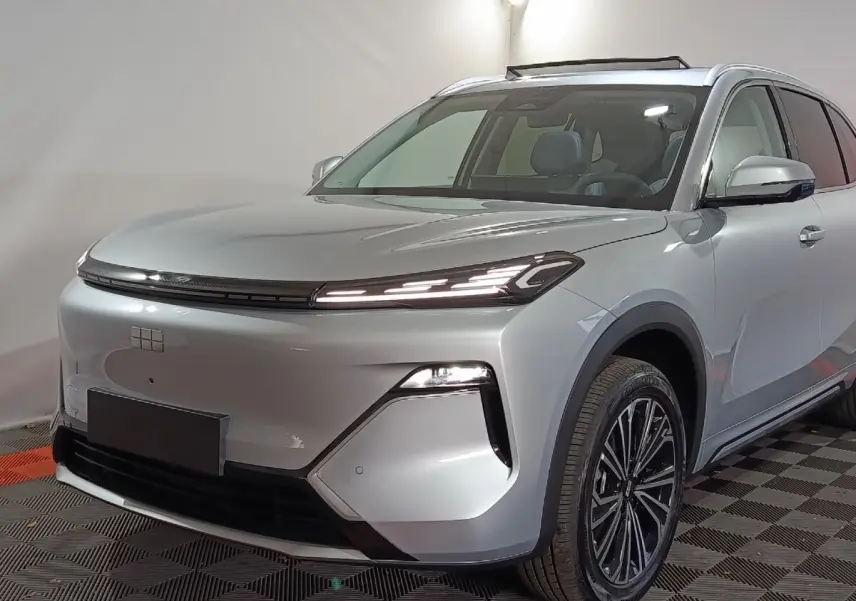 Vue 3/4 avant droit d'un SUV Geely STARRAY gris clair avec phares LED fins et toit vitré visible.