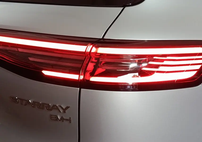Gros plan sur le feu arrière droit rouge allumé d’un Geely STARRAY gris clair avec logo et badge EM-I visible.