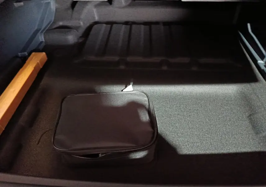Vue intérieure du coffre gris clair du Geely STARRAY 1.5 EM-I PHEV Max+ avec trousse noire et rangement latéral orange.