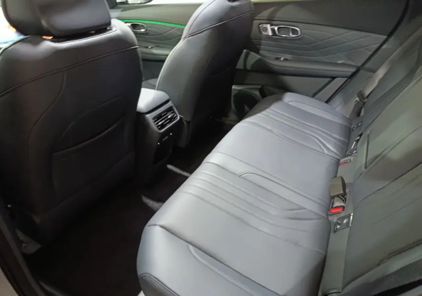 Vue intérieure arrière côté droit du Geely STARRAY 1.5 EM-I PHEV Max+ gris clair, sièges en cuir noir et accoudoir central.