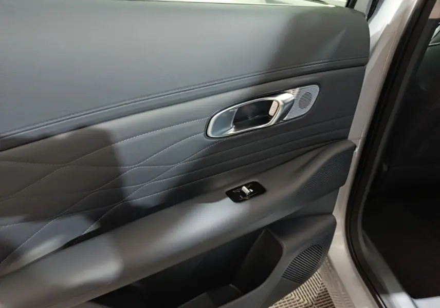 Gros plan sur la porte avant droite gris clair du Geely STARRAY 1.5 EM-I PHEV Max+ avec poignée et commande de vitre.