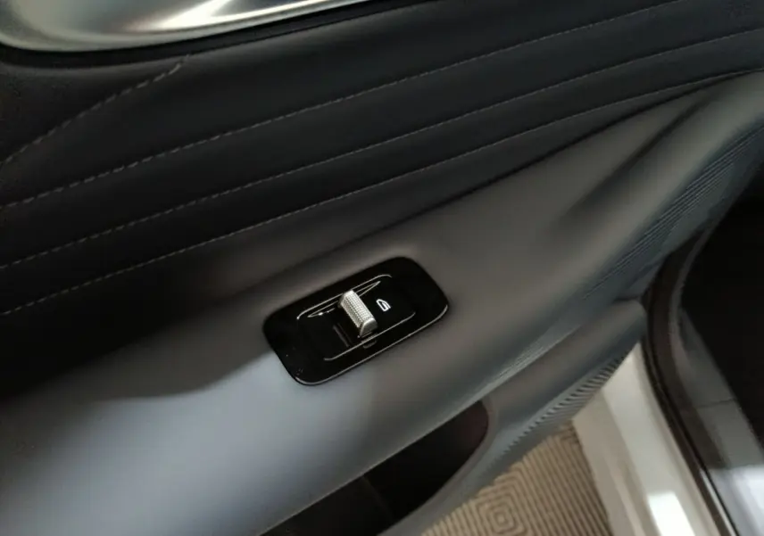 Détail du bouton de commande de la vitre sur la porte intérieure côté droit du GEELY STARRAY gris clair.