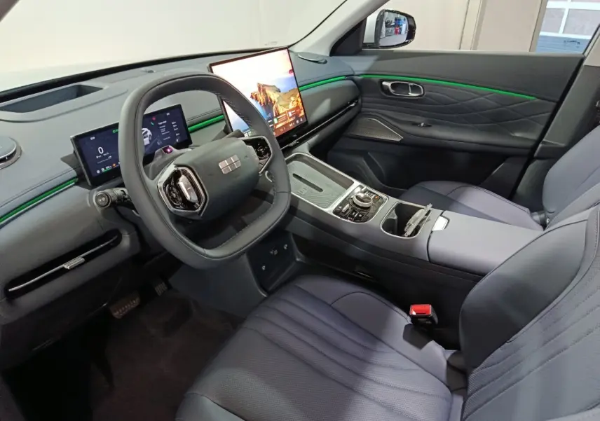 Intérieur avant droit du Geely STARRAY gris clair, tableau de bord avec écrans tactiles et éclairage d’ambiance vert.