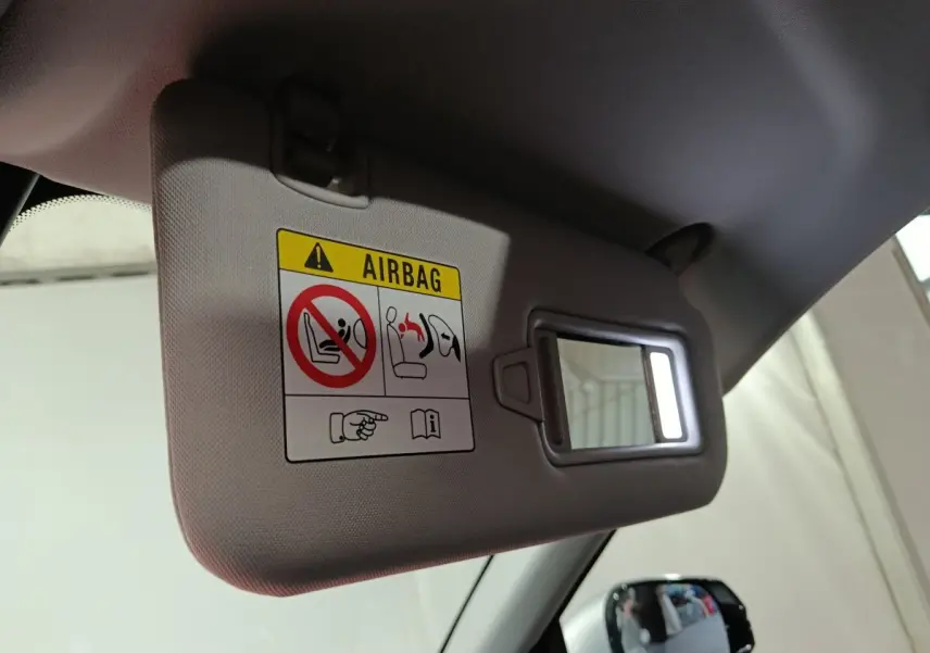 Détail intérieur du pare-soleil côté conducteur avec miroir éclairé et avertissement airbag dans un Geely Starray gris clair.