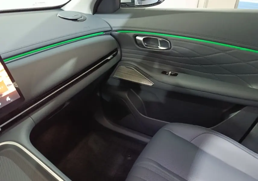 Intérieur côté passager du Geely STARRAY 1.5 EM-I PHEV Max+ avec éclairage d'ambiance vert et sellerie grise.