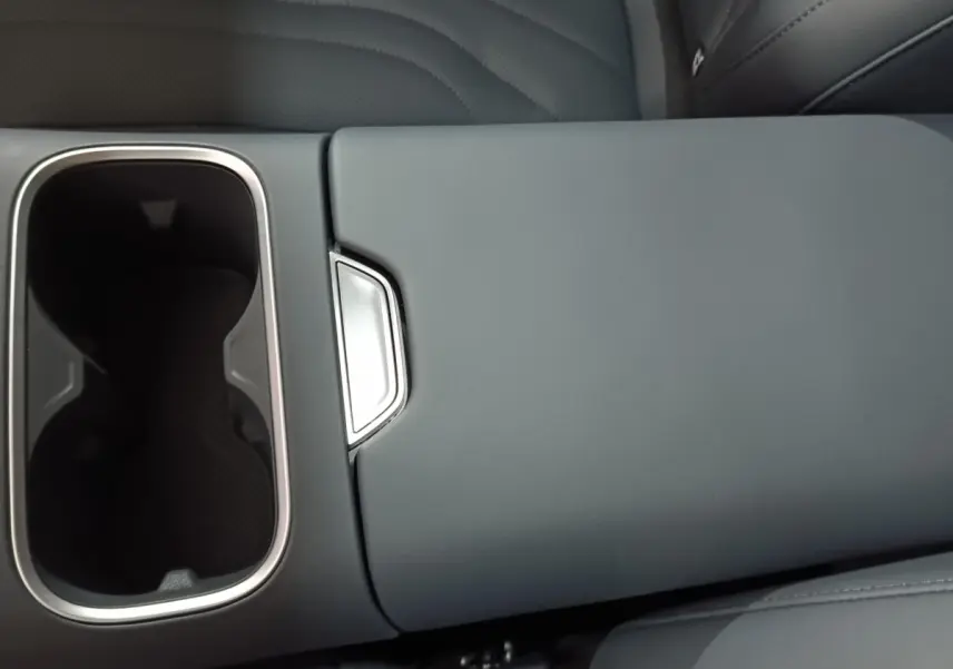 Gros plan sur l'accoudoir central gris clair avec porte-gobelets chromé intérieur d'un GEELY STARRAY 1.5 EM-I PHEV Max+