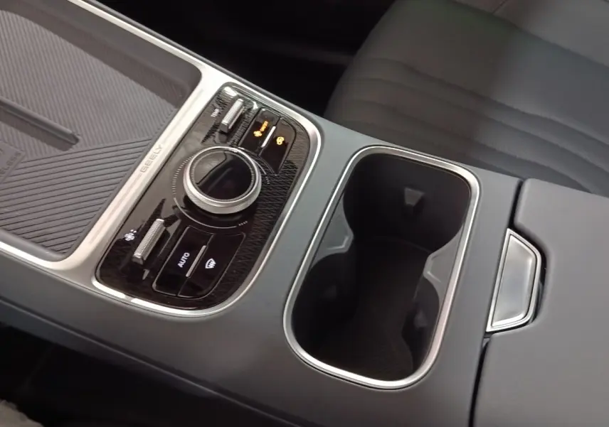 Gros plan sur la console centrale grise du Geely STARRAY 1.5 EM-I PHEV Max+ avec molette de sélection et porte-gobelets.