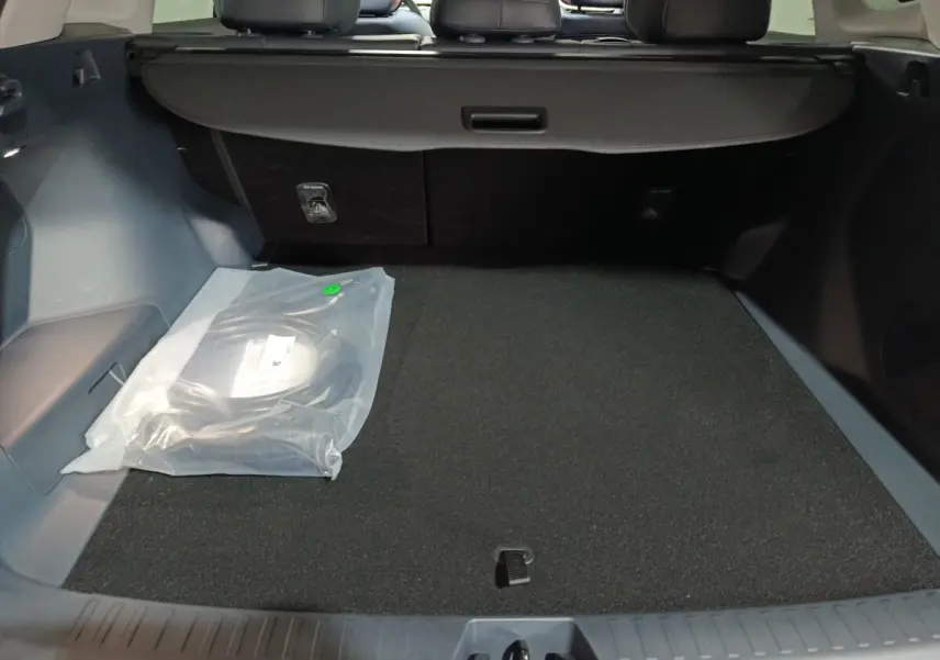 Coffre ouvert du Geely STARRAY gris clair, vue intérieure montrant la banquette arrière et un câble de recharge emballé.