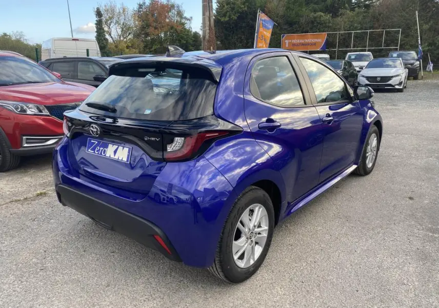 Toyota Yaris hybride 2025 bleu Genièvre vue 3/4 arrière droit avec jantes alliage 15 pouces et toit noir brillant.