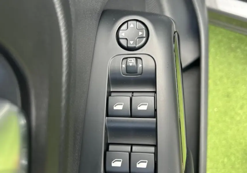 Gros plan sur les commandes de lève-vitres et réglage des rétroviseurs côté gauche d'une Citroën C5 Aircross 2025.