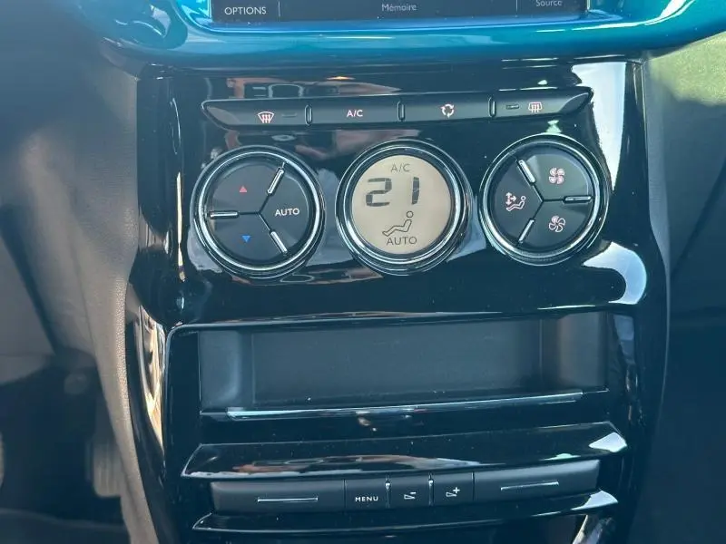 Gros plan sur la console centrale noire brillante du DS3 2016, affichant la climatisation automatique réglée à 21°C.