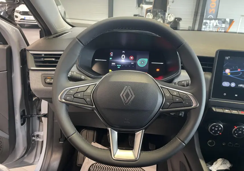 Vue intérieure centrée sur le volant noir de la Renault Clio 1.5 Blue dCi 2025, avec tableau de bord numérique et écran tactile.