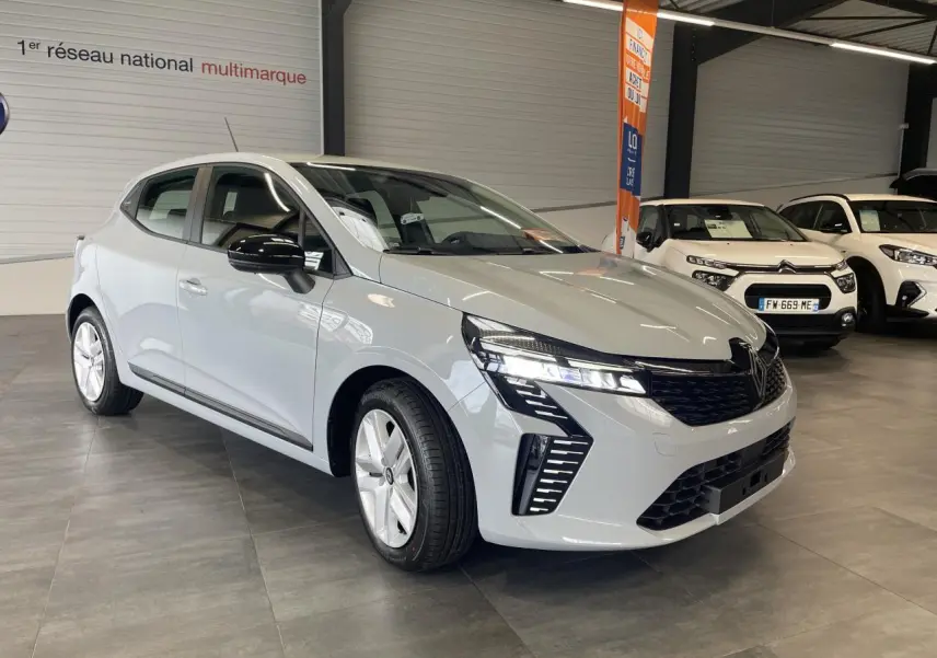 Renault Clio 2025 gris Rafale en 3/4 avant droit, avec calandre noire et feux LED distinctifs allumés.