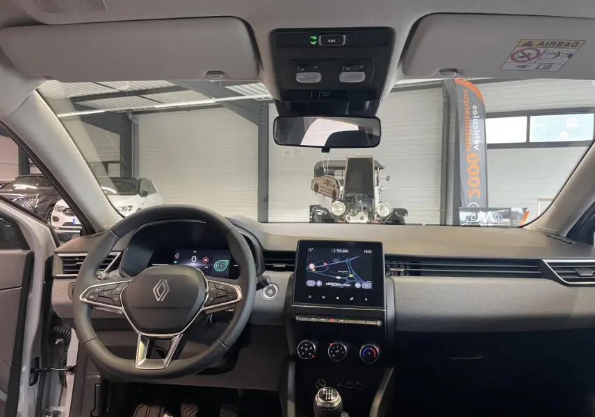 Vue intérieure avant de la Renault Clio 1.5 Blue dCi 2025, tableau de bord gris avec écran tactile 7 pouces et volant multifonction.