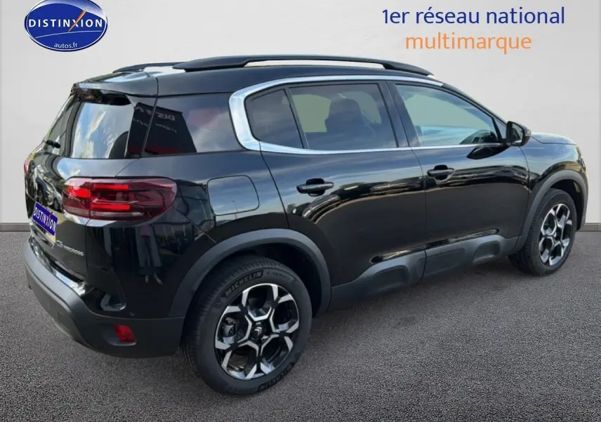 Vue 3/4 arrière droite du Citroën C5 Aircross noir Perla Nera avec barres de toit et jantes alu distinctives.