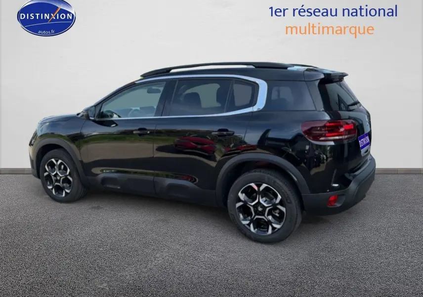 Vue latérale droite d'un Citroën C5 Aircross noir Perla Nera avec jantes alliage et barres de toit visibles.