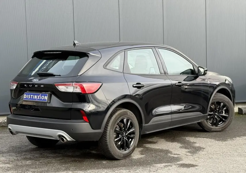 Vue 3/4 arrière droite du Ford Kuga 2024 noir Obsidien avec jantes noires et attelage rétractable visible.