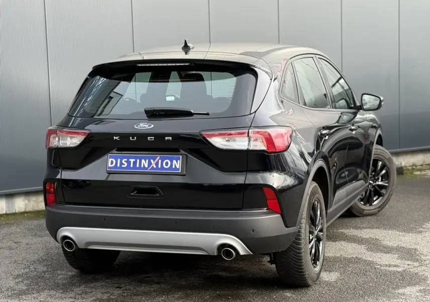 Vue 3/4 arrière droite du Ford Kuga 2024 noir Obsidien avec attelage rétractable et jantes alliage noires.