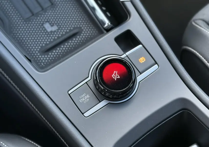 Gros plan sur la console centrale noire du Volkswagen T-Roc 2026, avec bouton start/stop et commande électronique de frein à main.