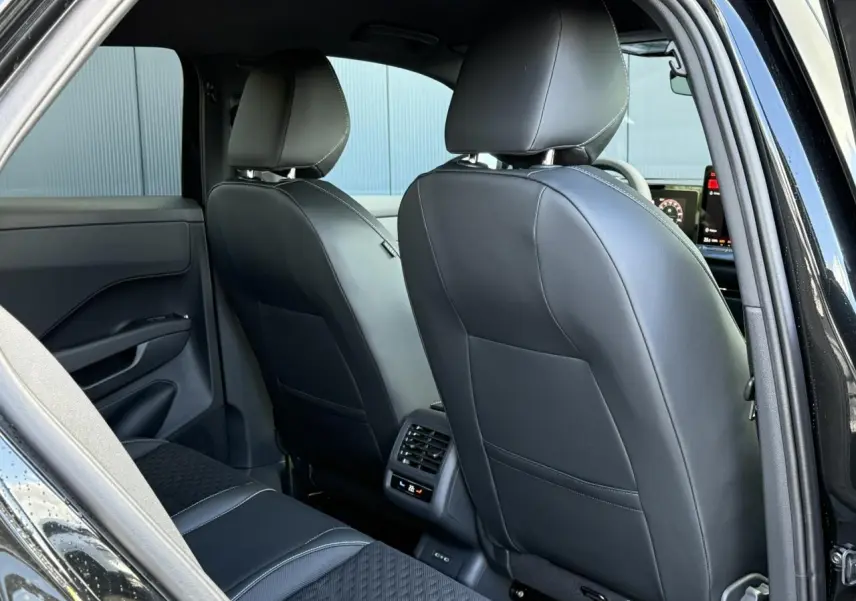 Vue arrière intérieure du Volkswagen T-Roc 2026 noir Ébène, sièges avant en cuir noir et ventilation arrière visible.