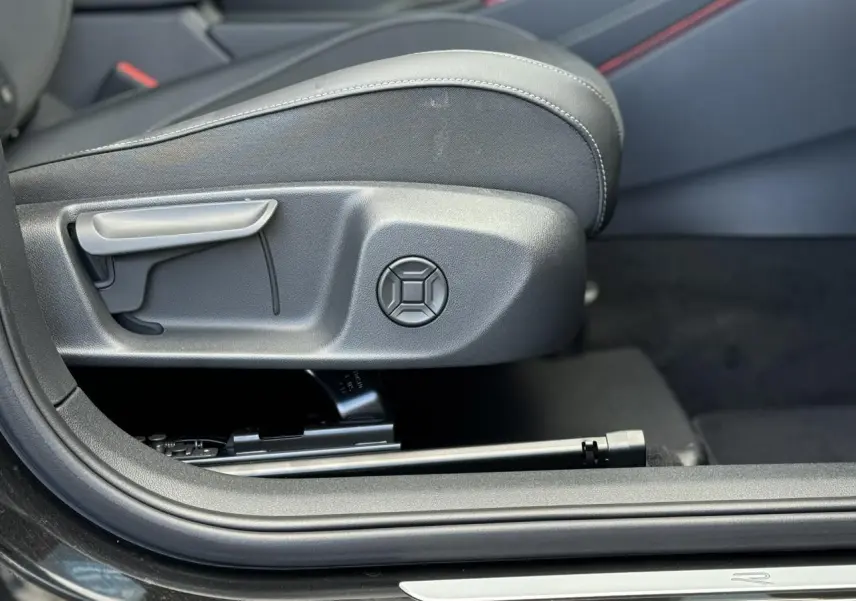 Gros plan sur le côté gauche du siège avant en tissu noir du Volkswagen T-Roc 2026 avec réglage manuel et surpiqûres grises.