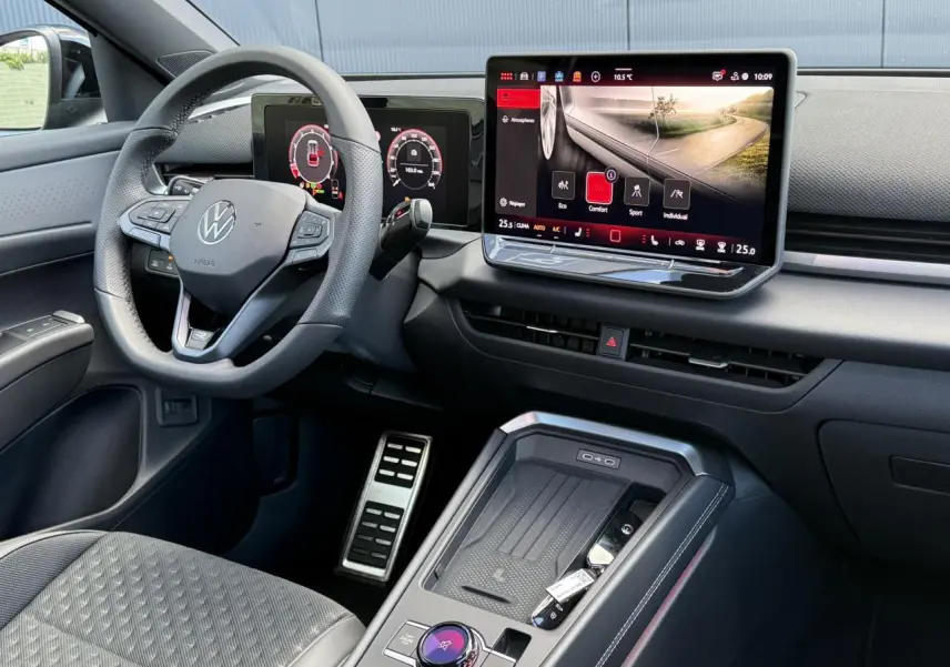 Vue intérieure côté conducteur du Volkswagen T-Roc 2026, tableau de bord numérique et écran tactile central avec volant cuir multifonction.