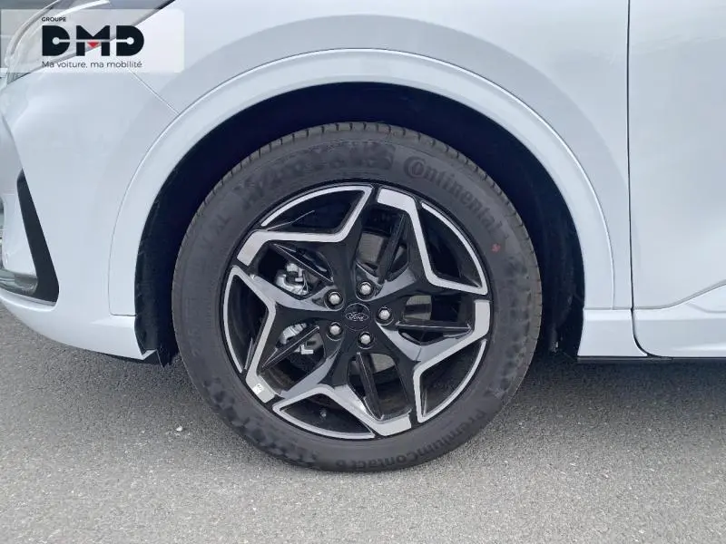 Gros plan sur la roue avant gauche du Ford Kuga blanc Glacier avec jante alu 19 pouces design ST-Line Ebony Black.