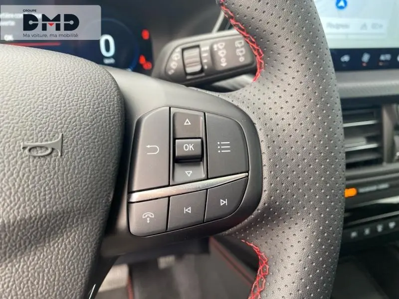 Gros plan sur les commandes multifonctions du volant perforé avec surpiqûres rouges du Ford Kuga blanc Glacier, intérieur moderne.