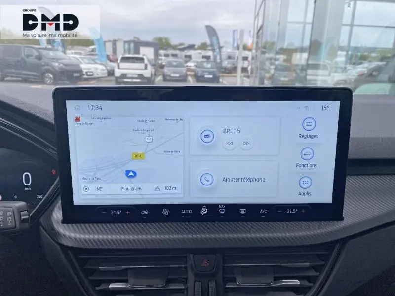 Écran tactile central du Ford Kuga 2026 blanc Glacier, affichant navigation et commandes multimédia, vue intérieure frontale.