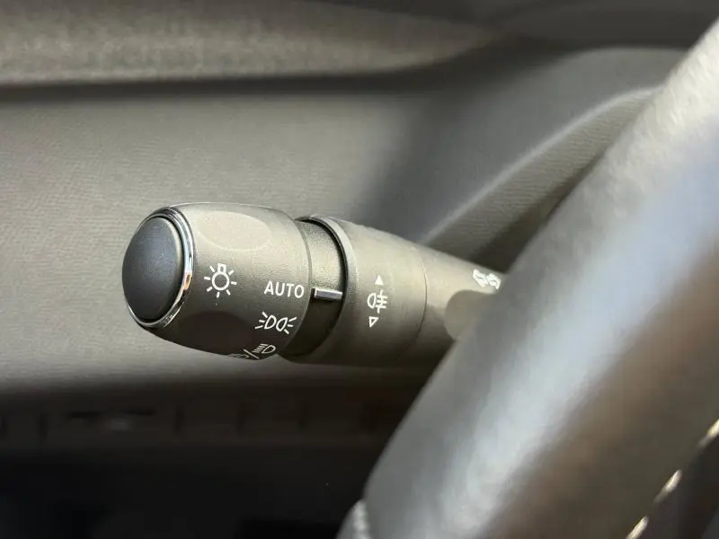 Gros plan sur la commande des phares automatique dans l'habitacle d'une Peugeot 308 noire 2024.
