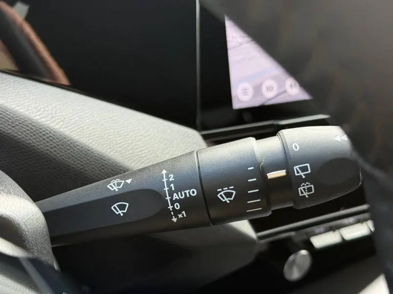 Gros plan sur la commande des essuie-glaces dans l’habitacle d’une Peugeot 308 noire, avec écran tactile en arrière-plan.