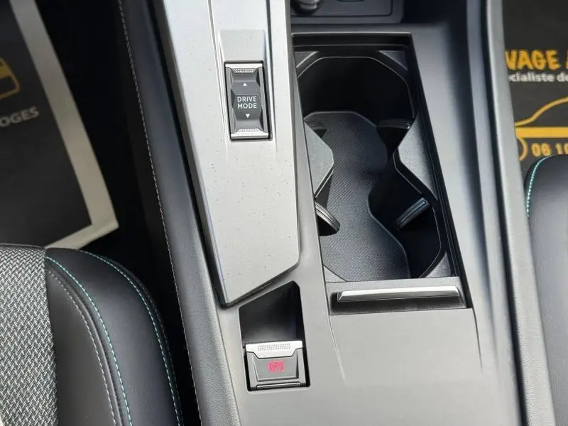 Gros plan sur la console centrale de la Peugeot 308 2024 noire, avec bouton Drive Mode et frein à main électrique.