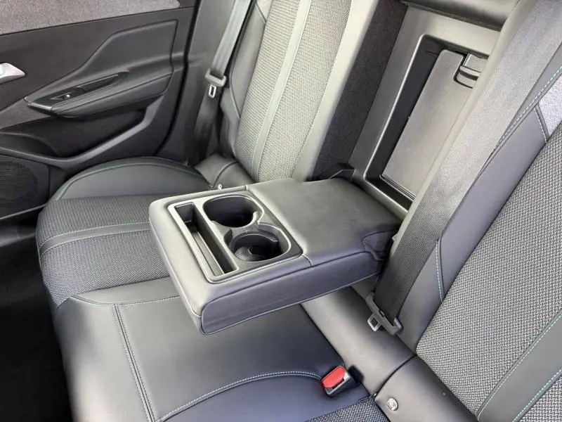 Vue rapprochée de la banquette arrière de la Peugeot 308 2024 avec accoudoir central rabattable et porte-gobelets intégrés.